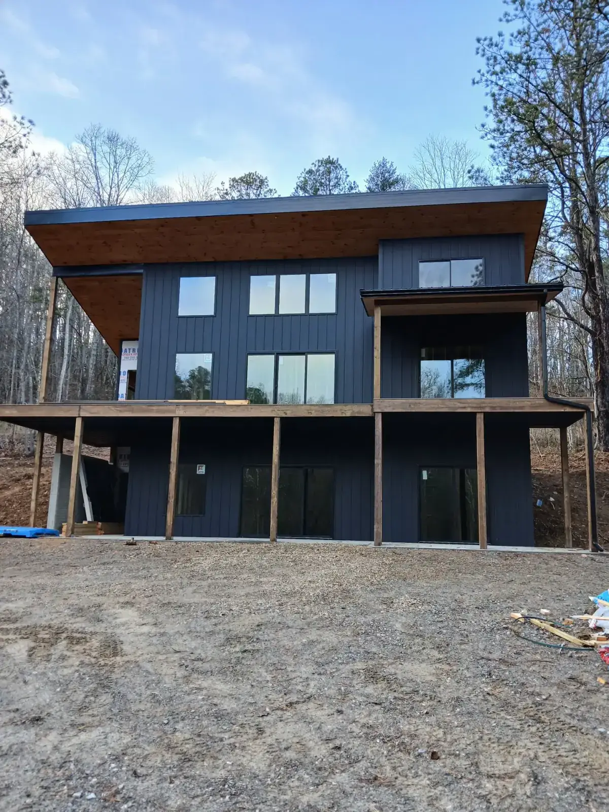 Modern black board and batten metal siding on a three-storey hillside home with cedar soffits