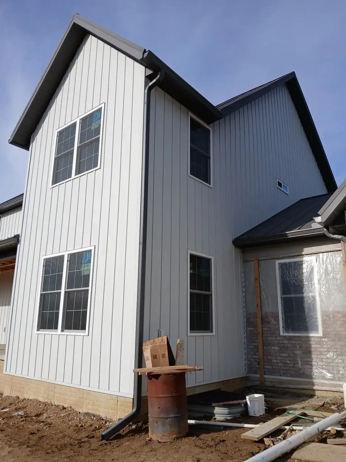 New two-storey Licking County home clad in grey board and batten metal siding with black metal roof