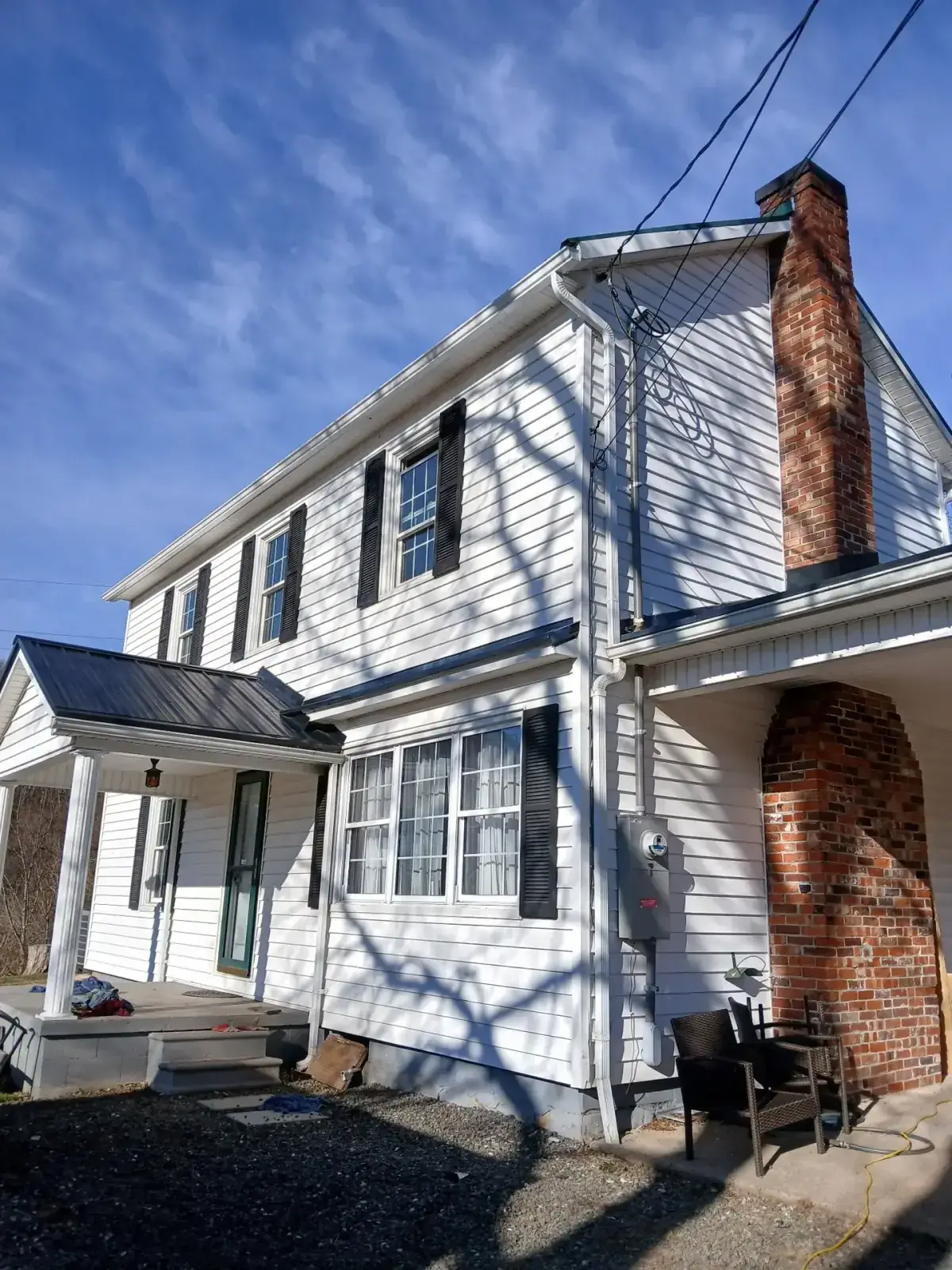 White farmhouse in Fairfield County with a new black metal porch roof and standing seam panels